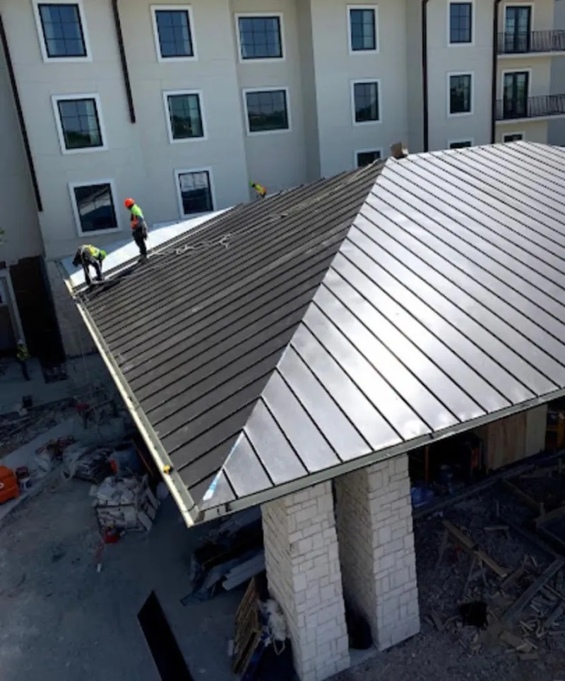 Crew installing standing seam metal roof panels on a commercial project in Merced